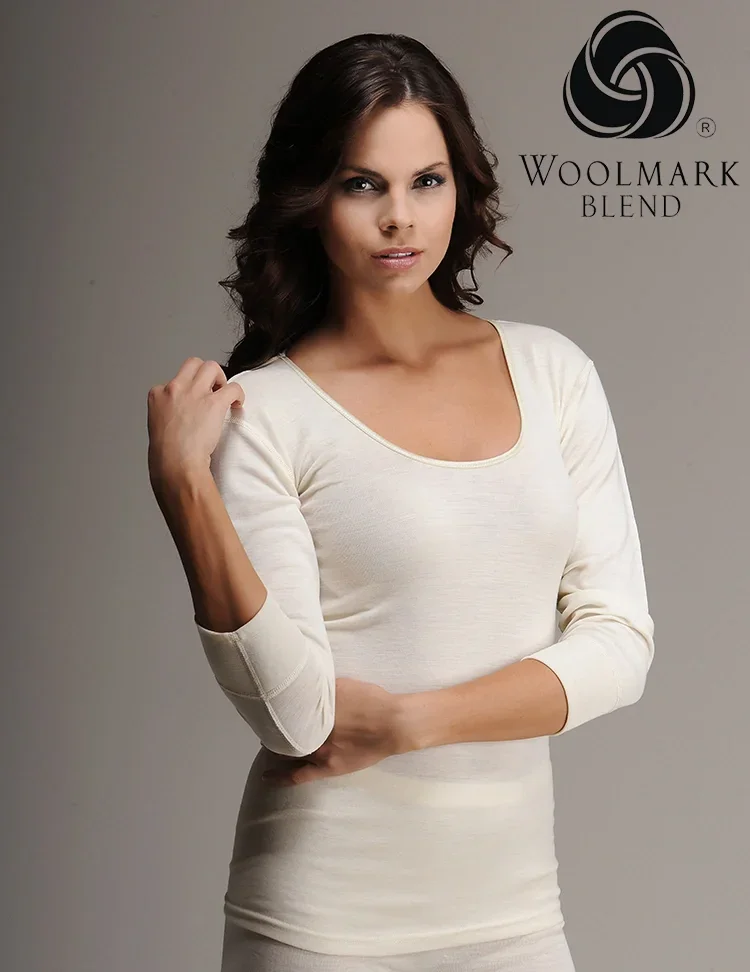 303%20-%20Women%27s%20Ribbed%20Wool%20Long%20Sleeve%20Top%20-%20303 Soft cream-colored long sleeve top worn by a female model with dark brown wavy hair, showcasing elegant casual fashion.