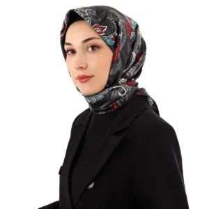 Black silk headscarf with colorful paisley patterns worn by a woman in a black suit, showcasing Turkish fashion and accessories. Perfect for stylish cultural or everyday wear.