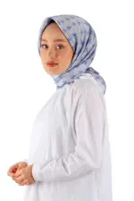 Soft blue patterned silk hijab styled on a woman, there is a white dress, on a plain white background.