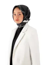 Elegant woman wearing a stylish black and white patterned silk hijab and a white blazer for a sophisticated look.