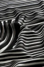 Black and white striped fabric with wavy folds, high-contrast pattern, modern design, soft texture, suitable for fashion or home decor.