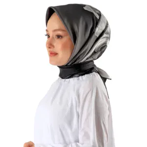 Elegant woman wearing a stylish black and gray silk headscarf, showcasing Turkish fashion and head coverings, against a clean white background.