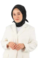 Elegant woman in a black hijab and white blazer, smiling confidently, showcasing modern Islamic fashion and professional style.