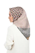 Elegant woman wearing a stylish patterned hijab with brown, black, and white geometric designs, paired with a white blazer, showcasing modest fashion from Turkey.