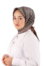 Elegant woman wearing a patterned silk hijab and a white button-up shirt, showcasing modest fashion style, on a plain white background.