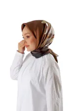 Elegant woman wearing a silky, patterned hijab in shades of brown, beige, and cream, paired with a white top, showcasing modest fashion and Turkish heritage styles.