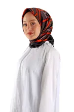 Elegant woman wearing a stylish black and red patterned silk hijab, paired with a flowing white dress, showcasing modern fashion from Turkey. Perfect for online shopping and fast shipping at Shop of Turkey.
