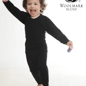 Bright happy child dancing in black pajamas with Woolmark Blend logo in studio setting.