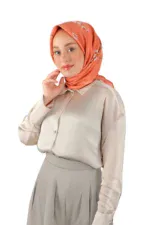 Elegant woman wearing a silky beige blouse and matching pleated skirt with a coral floral hijab, showcasing stylish modest fashion from Turkey.