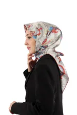 Elegant woman wearing a patterned silk hijab in red, blue, and gray tones, paired with a classic black blazer, showcasing stylish modest fashion from Turkey with a focus on quality and fast shipping.