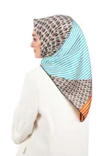 Vibrant multicolored patterned hijab with geometric and striped designs, worn by a woman in a white blazer, showcasing Turkish fashion styles.