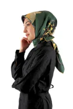 Silk floral patterned hijab in green, black, and gold, styled on a woman with a thoughtful expression, wearing a black satin shirt. Perfectly showcases elegant Turkish fashion accessories available at Shop of Turkey.