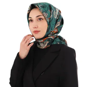 Vibrant patterned silk hijab in shades of teal, white, and orange worn by a woman in a black blazer, symbolizing elegance and cultural fashion with a focus on high-quality Turkish textile craftsmanship.