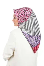 Colorful patterned silk hijab with pink, purple, black, and white geometric and striped designs, styled on a woman in a white blazer for elegant Islamic fashion.