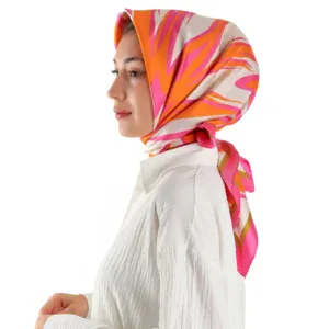 Vibrant pink, orange, and cream silk scarf tied around a smiling woman's head, showcasing elegant and colorful headwear fashion.