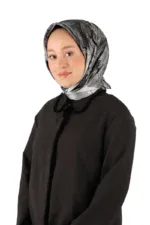 Elegant woman wearing a stylish black coat and a gray marble-patterned headscarf, representing Turkish fashion and cultural attire, against a plain white background.