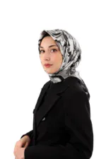 Elegant woman wearing a stylish black blazer and a silk floral hijab, showcasing modern modest fashion with a clean white background.