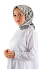 Soft gray and white patterned silk scarf worn by a smiling woman in a white top, showcasing elegant headwear.