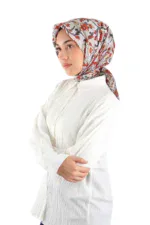 A young woman wearing a colorful floral patterned silk headscarf and a white textured long-sleeve blouse, posing against a plain white background for a fashionable and stylish look.