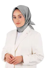 Elegant woman wearing a light gray silk hijab and a white blazer, showcasing modest fashion, with soft lighting and a clean background.