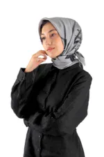 Silk gray hijab with black floral pattern styled with a black button-up shirt, fashionably worn by a young woman with a thoughtful expression, showcasing modest fashion for women.