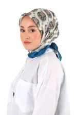 Elegant woman wearing a stylish patterned silk headscarf with a blue border, dressed in a white blouse, showcasing Turkish fashion accessories for a sophisticated and modern look.