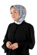 Elegant woman wearing a stylish gray patterned silk hijab and black smart casual blouse, demonstrating fashionable modest head covering for women.