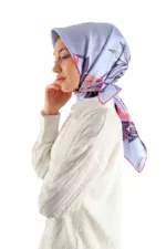Elegant woman wearing a colorful silk scarf with floral pattern, styled for a sophisticated look, on a plain white background.