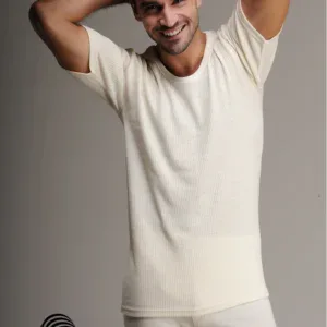 Soft cream ribbed t-shirt worn by smiling man with hands behind head, casual look, Woolmark logo, minimal background, emphasizing comfort and quality.