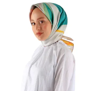 Vibrant turquoise and beige striped silk hijab styled on a woman with natural makeup, white blouse, and a confident expression. Perfect for elegant modest fashion and cultural style.