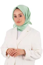 Elegant woman wearing a light green satin hijab and white blazer, demonstrating modest fashion and style for professional or everyday wear.