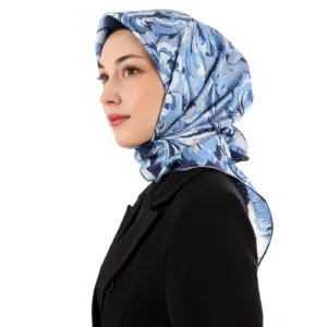 Blue floral patterned silk hijab styled on a woman with a black blazer, showcasing elegant modest fashion from Turkey. Perfect for stylish and cultural occasions.