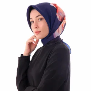 Elegant woman wearing a stylish navy blue hijab with a colorful floral accent, dressed in a black top, showcasing modest fashion with a modern touch.