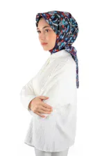 Elegant woman wearing a colorful floral patterned hijab and a white textured blouse, showcasing modest fashion with traditional Turkish influence. Perfect for stylish, cultural, and modern looks.