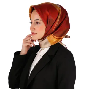 Vibrant red, orange, and beige patterned silk scarf worn by a woman in formal black blazer and white shirt, showcasing elegant Turkish scarf fashion.