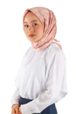 Soft pink silk hijab with floral pattern, worn by a woman with a white blouse and navy skirt for elegant modest fashion.