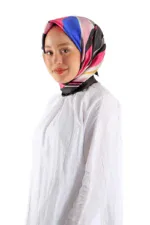 Colorful silk hijab with pink, blue, black, and beige stripes worn by a smiling woman in a white blouse. Perfect for modest fashion and elegant style.