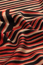 Vibrant black, white, and red striped fabric with a smooth texture, showcasing a stylish pattern perfect for fashion or home décor projects.
