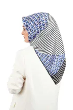 Elegant woman wearing a stylish blue and black patterned hijab with white striped accents, paired with a white blazer, showcasing modest fashion from Turkey.