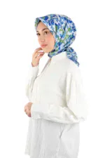 Blue floral patterned silk scarf worn by woman in white blouse, fashion accessories from Turkey, colorful head covering for women, stylish and elegant hijab, traditional Turkish scarf for women.