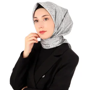Elegant woman wearing a stylish patterned hijab and black blazer, posing confidently for a fashion or lifestyle shoot.