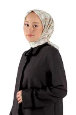 Soft beige silk headscarf with gold floral patterns paired with a black coat, showcasing stylish modest fashion from Turkey, available for purchase with fast international shipping.