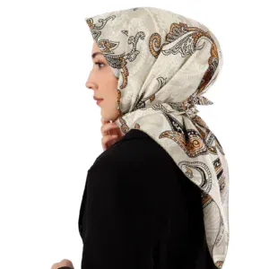 Elegant woman wearing a stylish patterned silk scarf wrapped around her head, showcasing a blend of intricate designs in neutral tones, ideal for fashion and cultural accessories.
