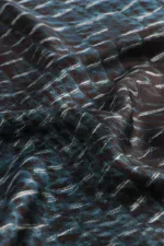 Dark blue crinkled satin fabric with glossy finish, textured surface, and reflective sheen for luxury fashion or home décor.