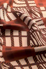 Vibrant geometric pattern textile featuring earthy tones of brown, beige, and black with zebra and plaid inspired designs, showcasing high-quality fabric perfect for fashion or home decor.