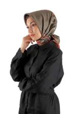 Elegant woman wearing a stylish silk patterned hijab and black shirt, showcasing modest fashion inspired by Turkish design, on a white background.