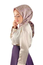Elegant woman wearing a beige satin blouse and purple hijab with geometric patterns, showcasing modest Turkish fashion.
