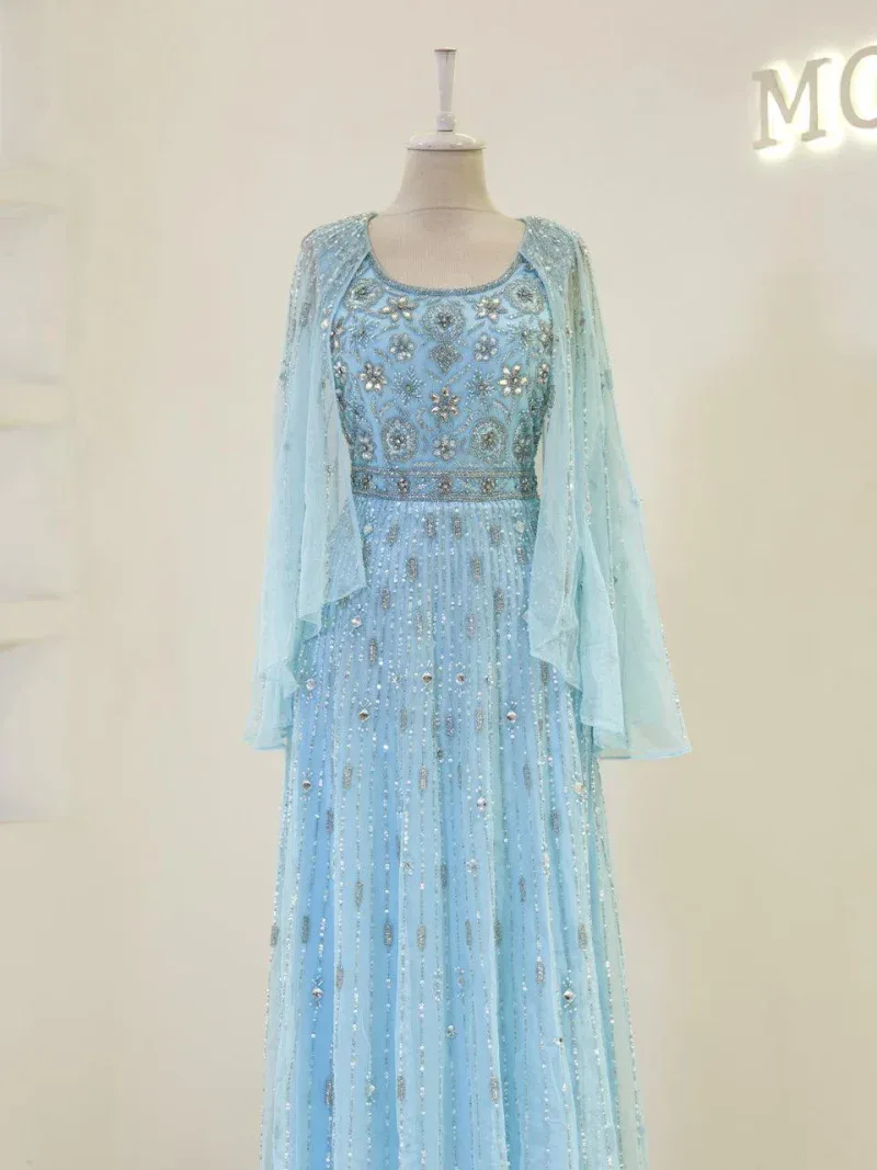 Meticulously crafted traditional dress featuring intricate embroidery and beadwork in soft blue hues, perfect for special occasions and celebrations.