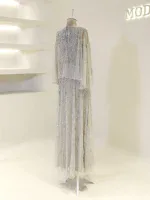 Luxurious cream-colored dress with intricate beadwork, long flowing sleeves, and a layered skirt, perfect for special occasions or weddings.