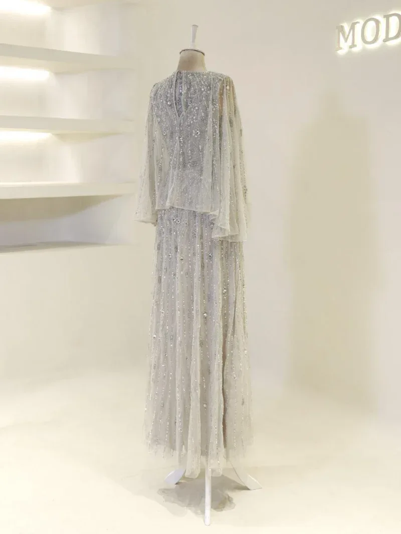 Luxurious cream-colored dress with intricate beadwork, long flowing sleeves, and a layered skirt, perfect for special occasions or weddings.